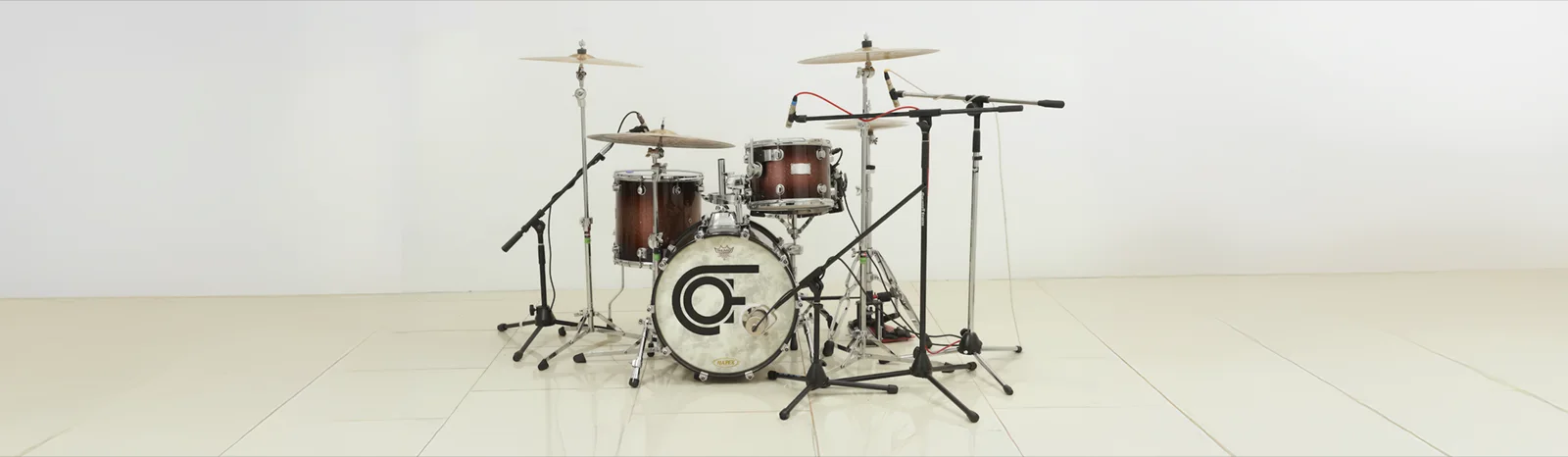A drum kit is in a spares, white room, miked up.