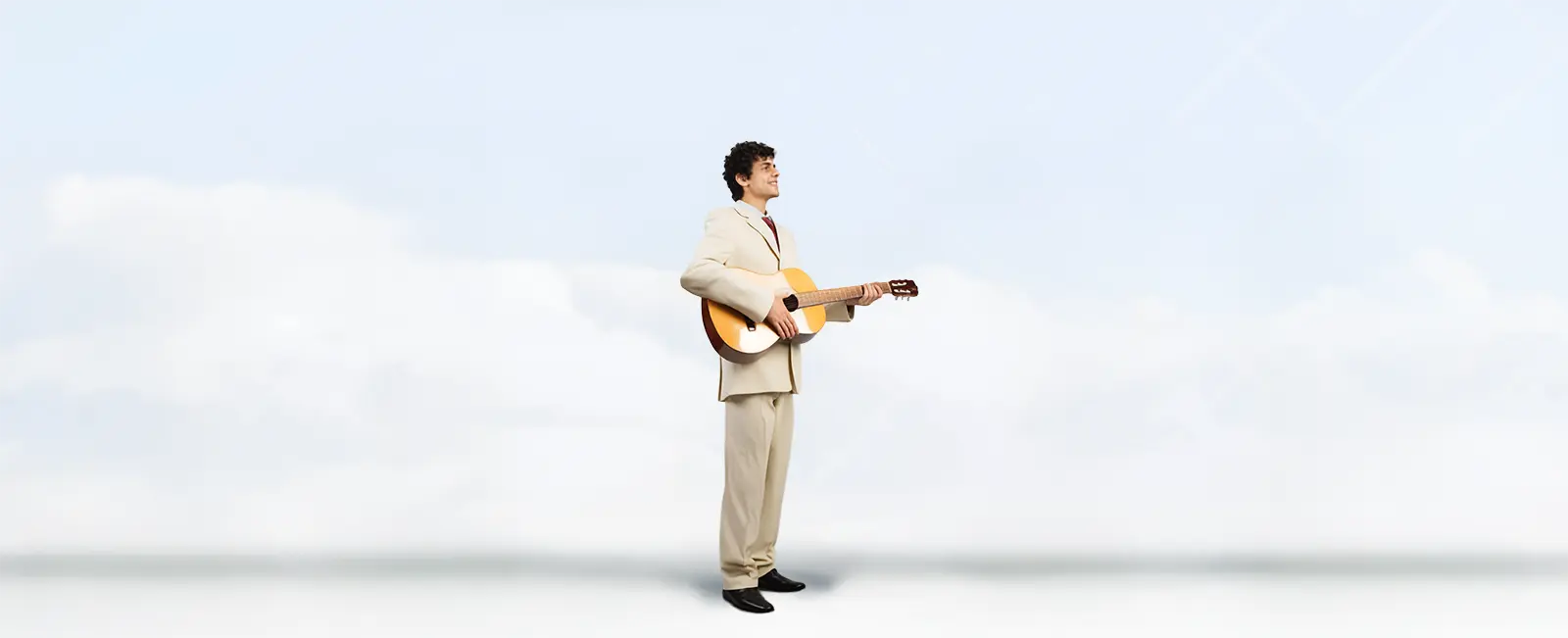 A single musician in a tan suit playing a guitar.